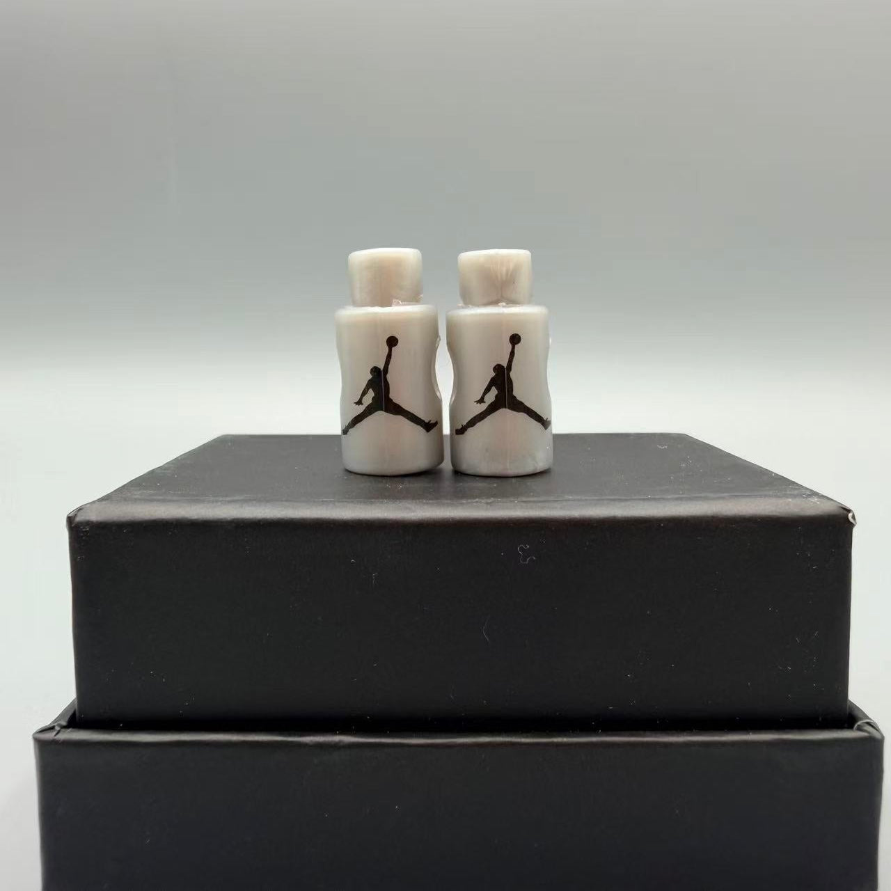 Two small grey lace locks with a logo on top of a black box against a gray background