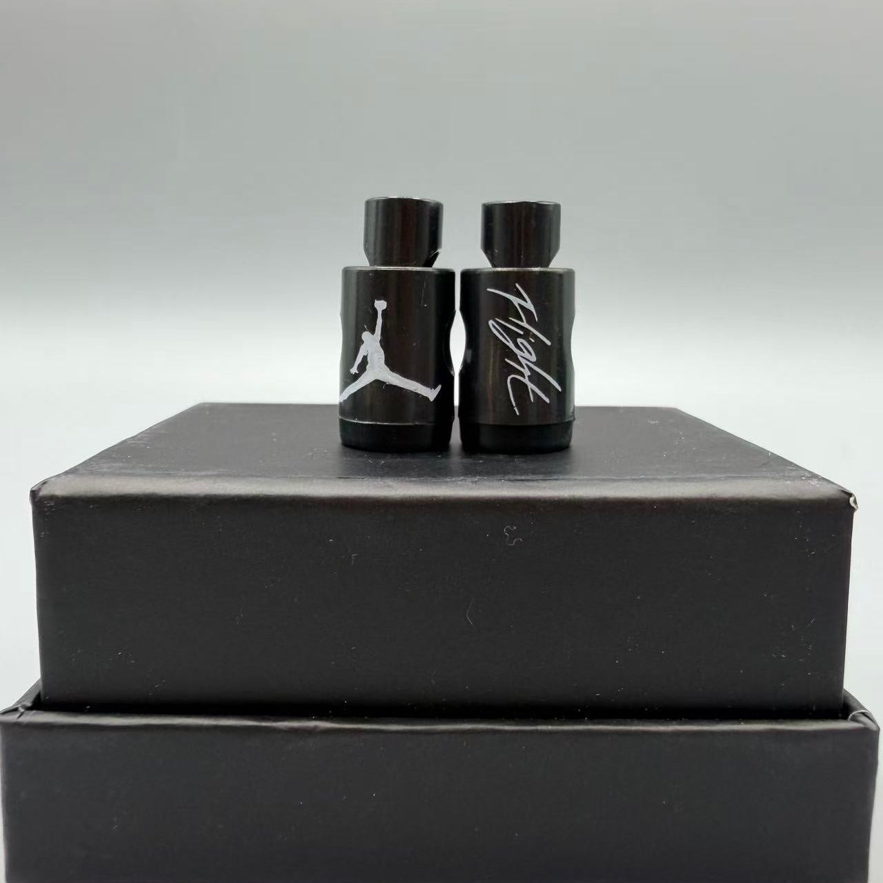 Black and white Jordan lace locks for sneakers on a black box with a gray background