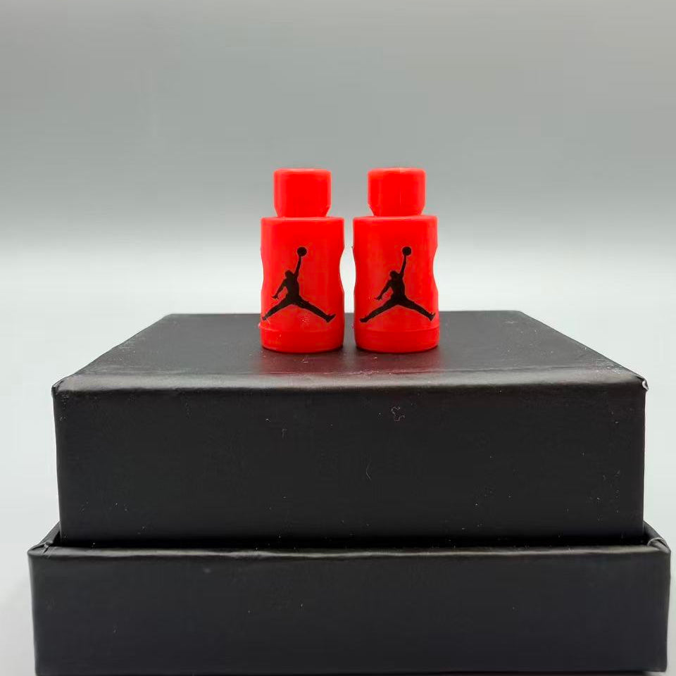 Two red Jordan jumpman shoe lace locks on a black box with a gray background
