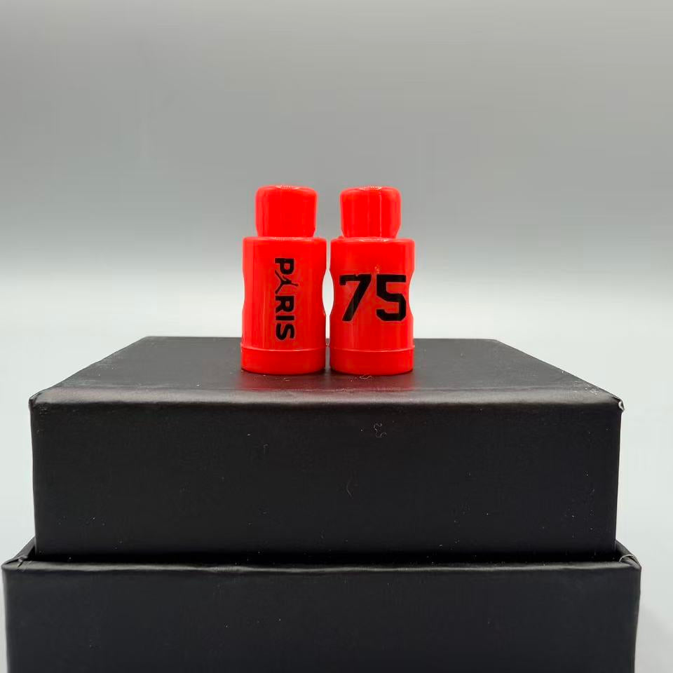 Two red lace locks with 'PARIS' and '75' printed on them, placed on a black box against a gray background.