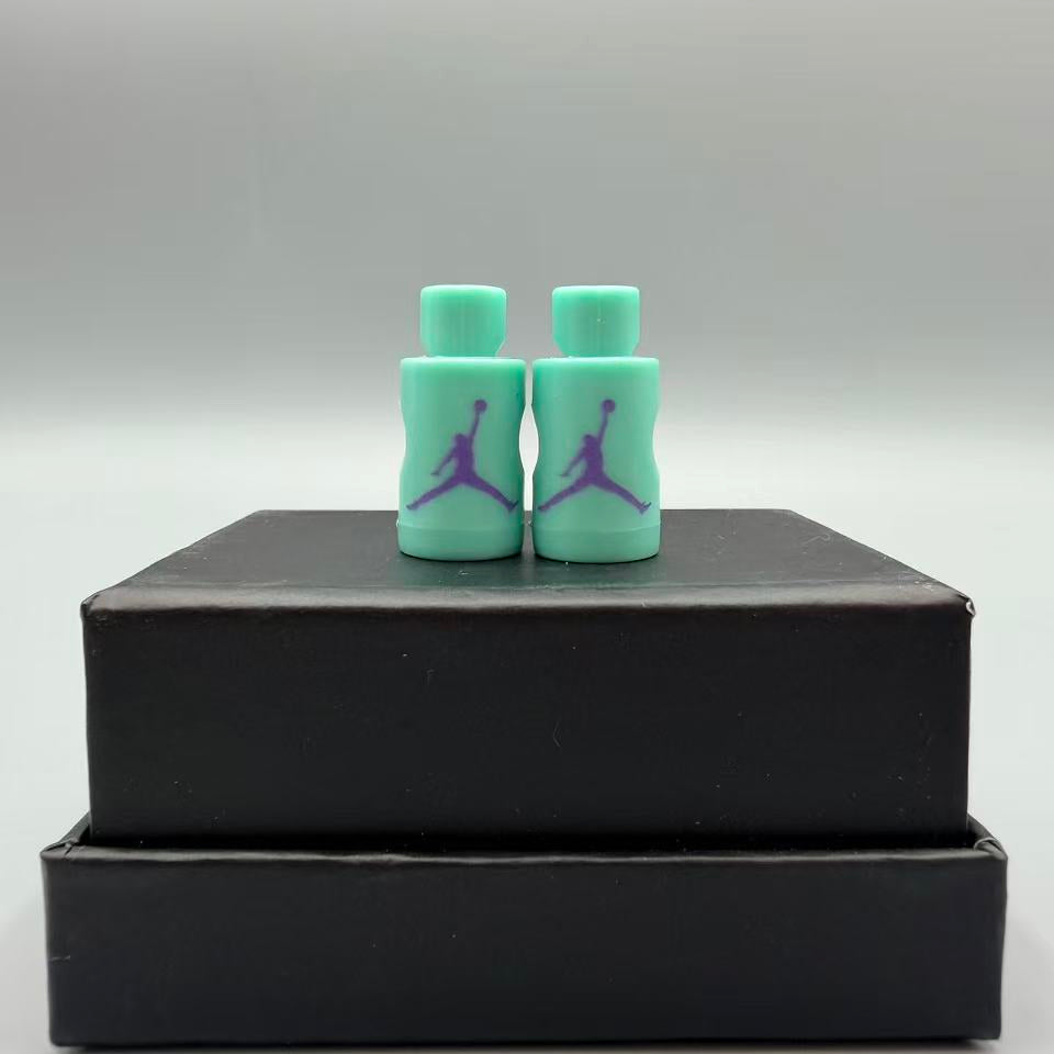 Two turquoise Jordan jumpman lace locks on a black box with a gray background